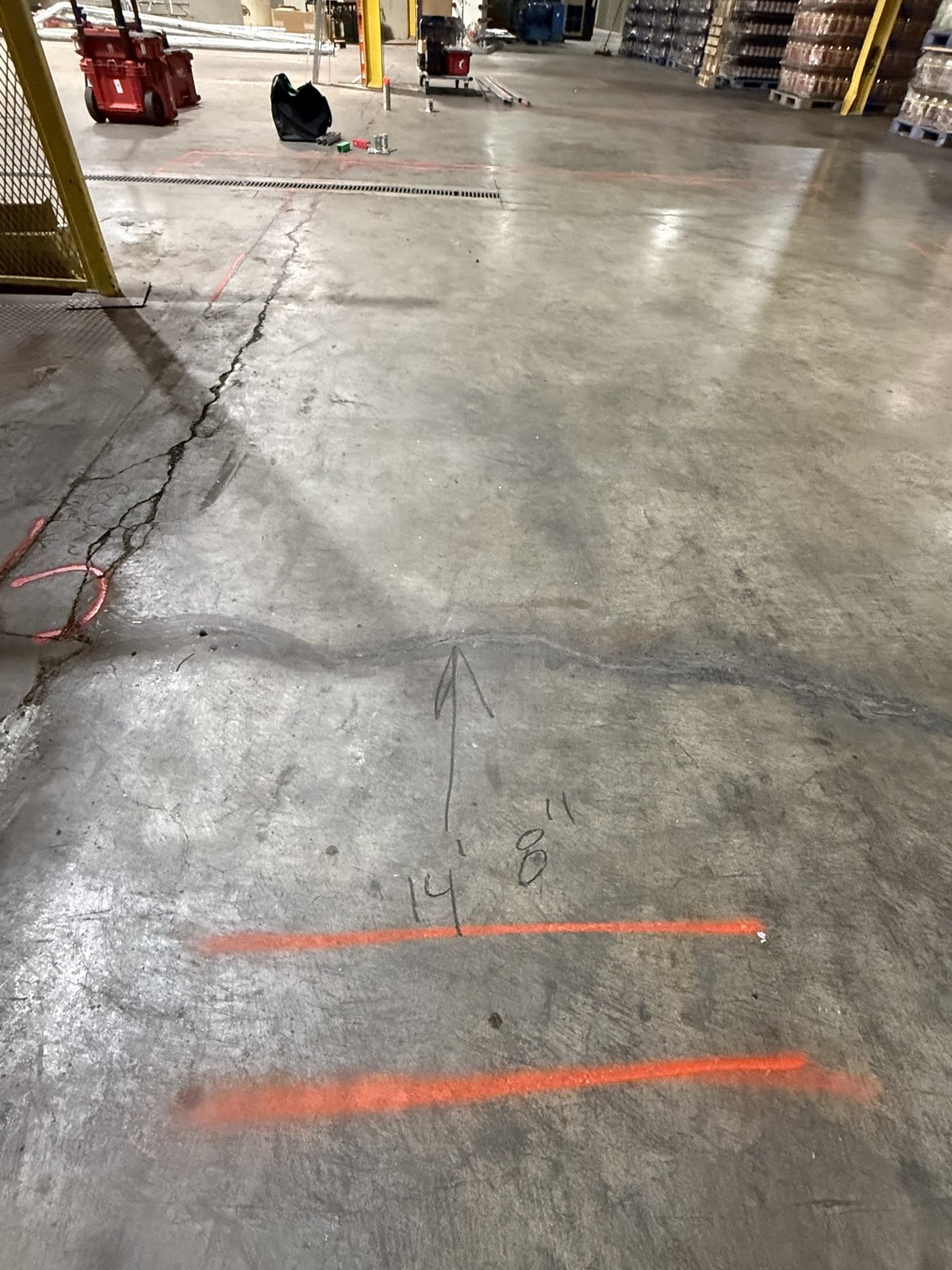 Cracked and worn concrete slab in a bottling plant can-line footprint before repair
