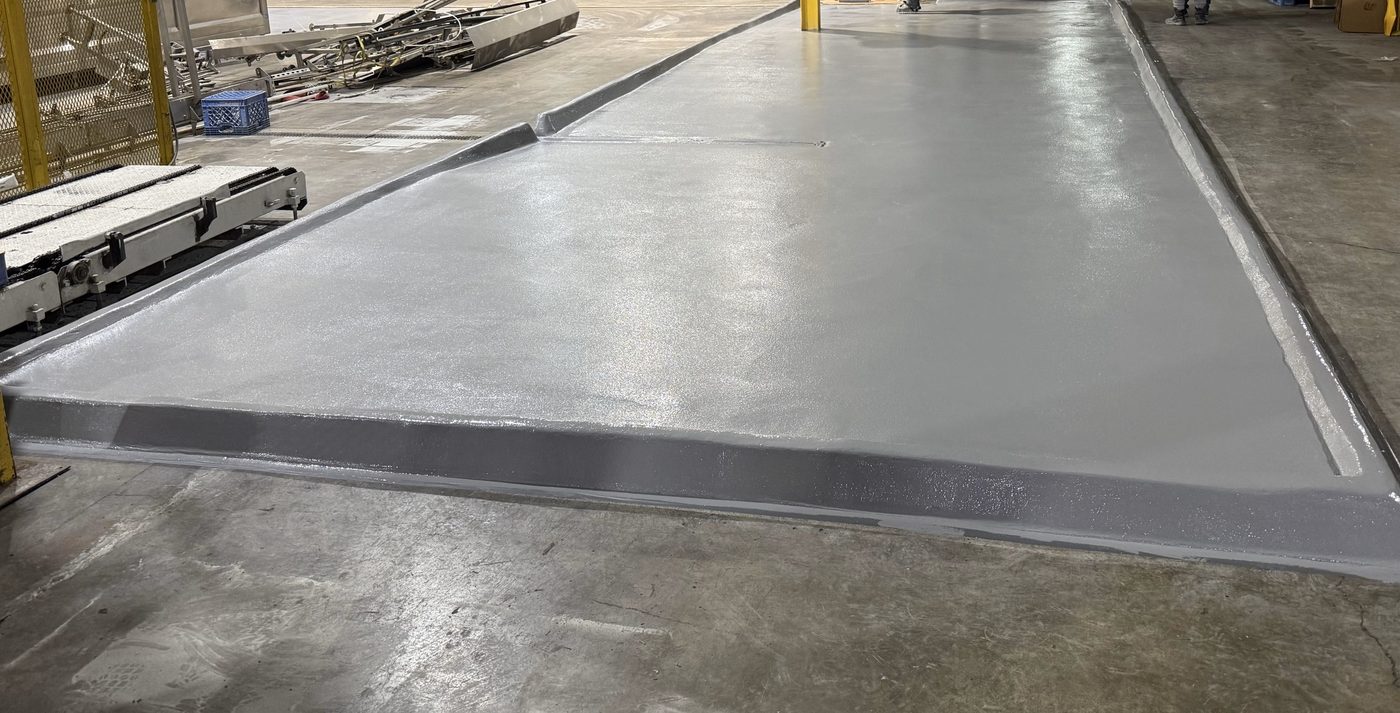 Finished sloped urethane cement pad with integral containment curb at a bottling plant