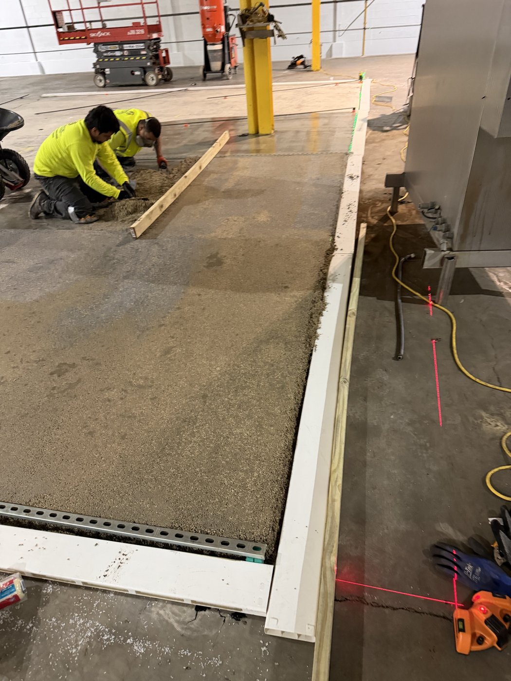 Crew screeding the sloped urethane overlay to grade against the curb form