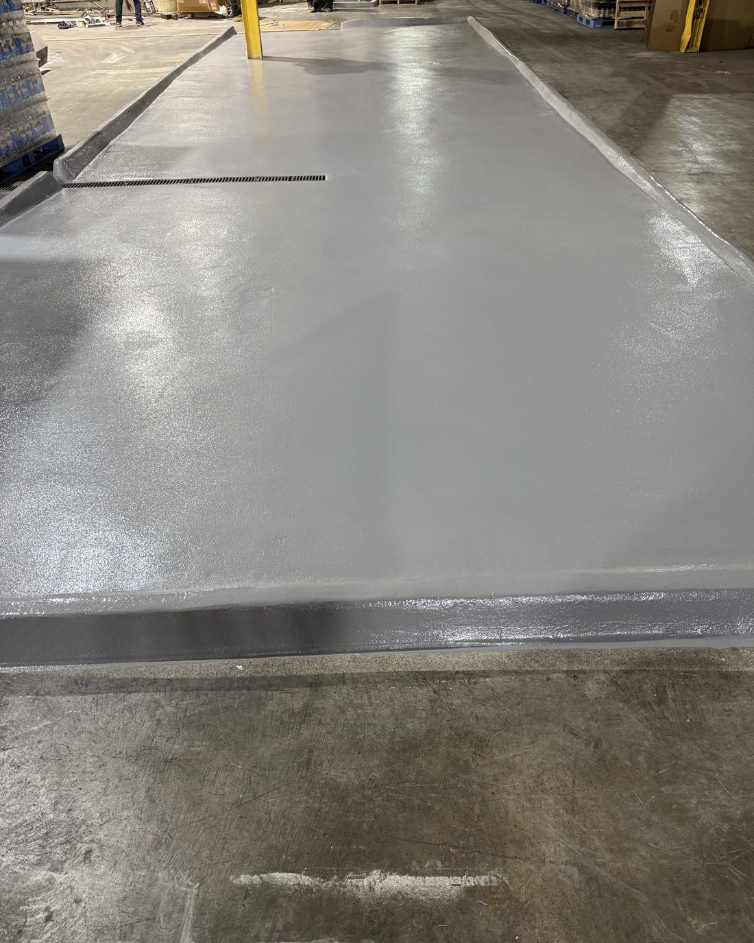 Raised process platform rebuilt with slope grout, urethane mortar, and polyaspartic topcoat, with trench drain
