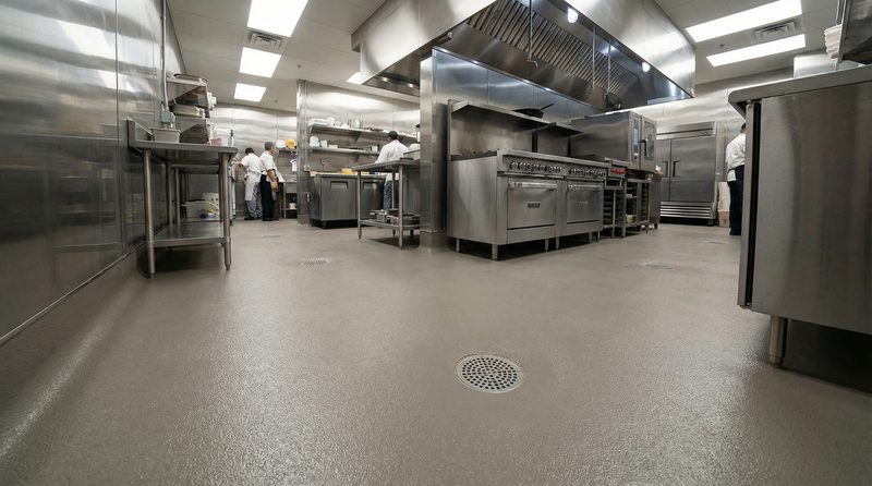 Commercial kitchen with cooks working on a seamless MavCrete urethane cement floor with floor drain